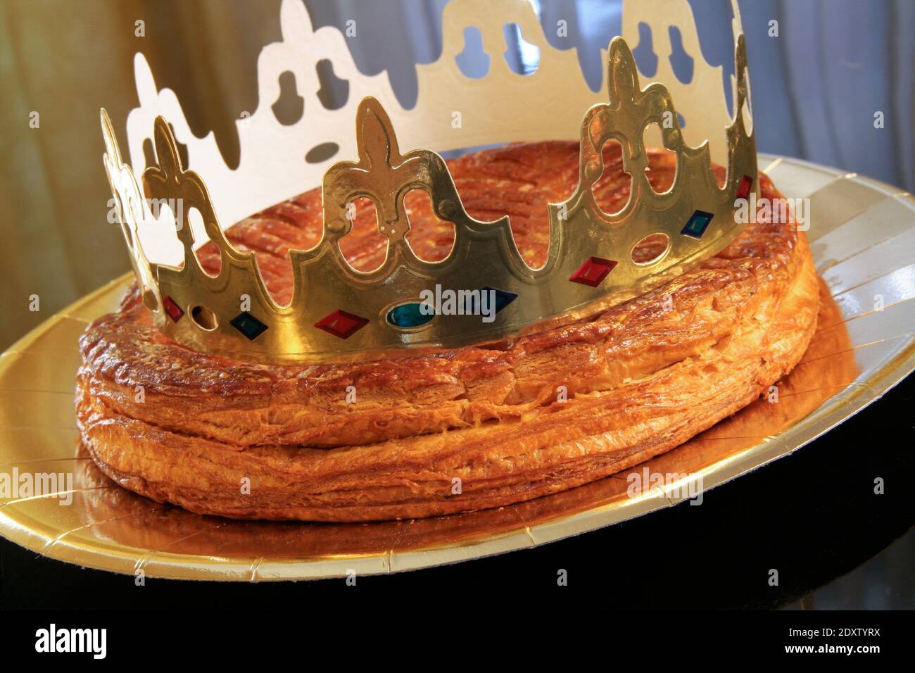 Galette des rois, French king's cake with a golden crown placed on it and presented on a golden plate - Stock Image
