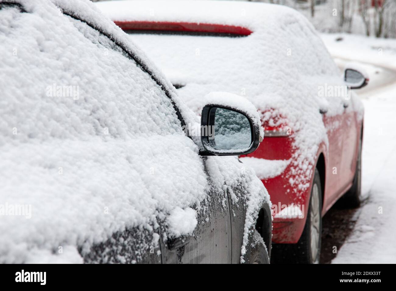 A closeup of modern cars parked on the side of the road covered in snow ...