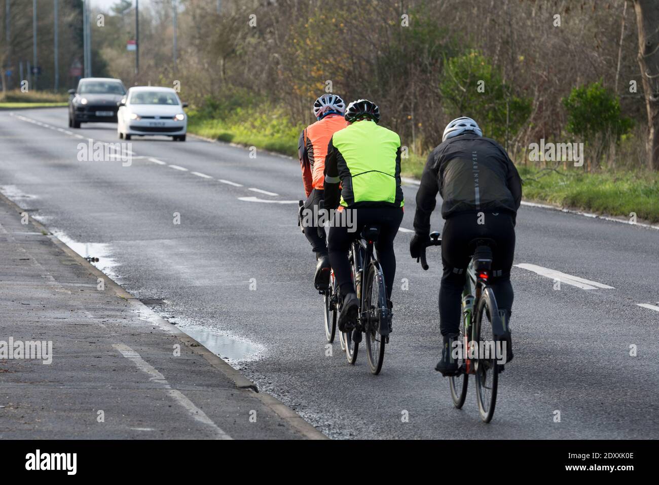 Rear view of male cyclists on a road in winter, Warwick, Warwickshire, England, UK Stock Photo