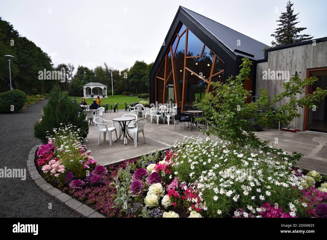 Café Laut in Akureyri Botanical Garden, Northern Iceland.  Flowerbeds surround the patio filled with chairs and tables in front of the modern building. Stock Photo