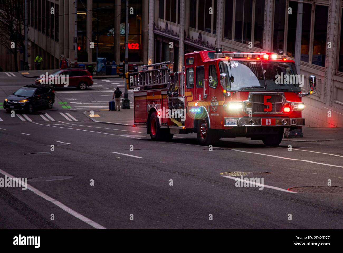 Seattle, WA—March 22, 2019; red municipal fire department truck driving up hill with lights and sirens as it responds to an emergency downtown among h Stock Photo