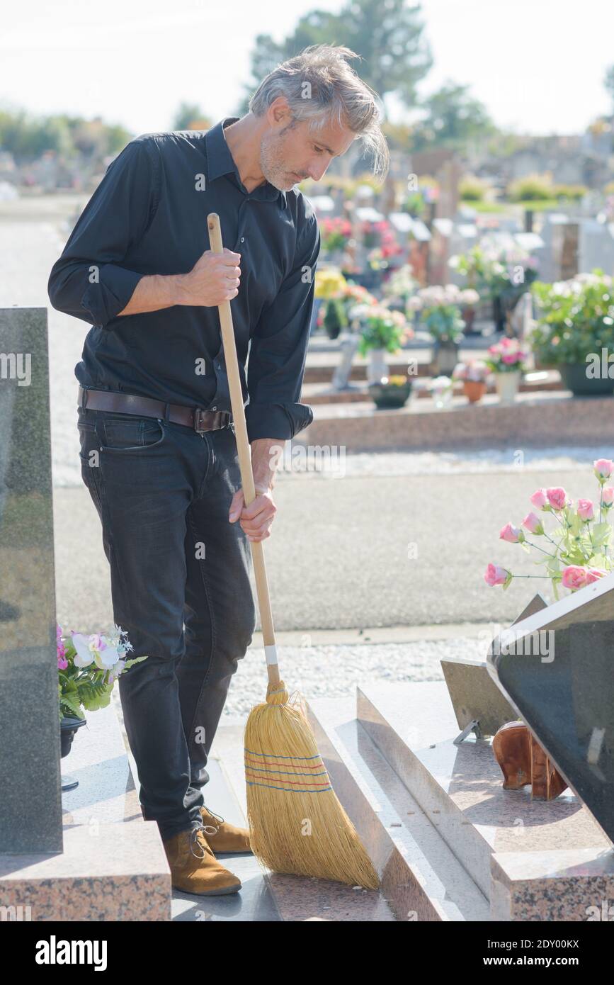 Man cleaning around grave in cemetery Stock Photo Alamy