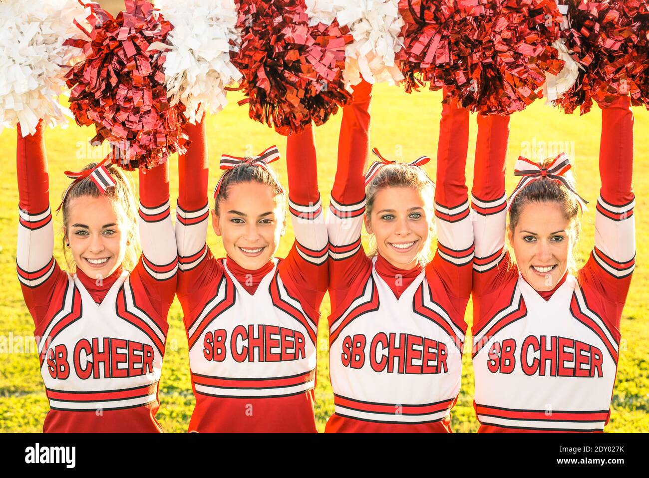 Portrait Of Happy Cheerleaders Holding Pompoms While Performing On