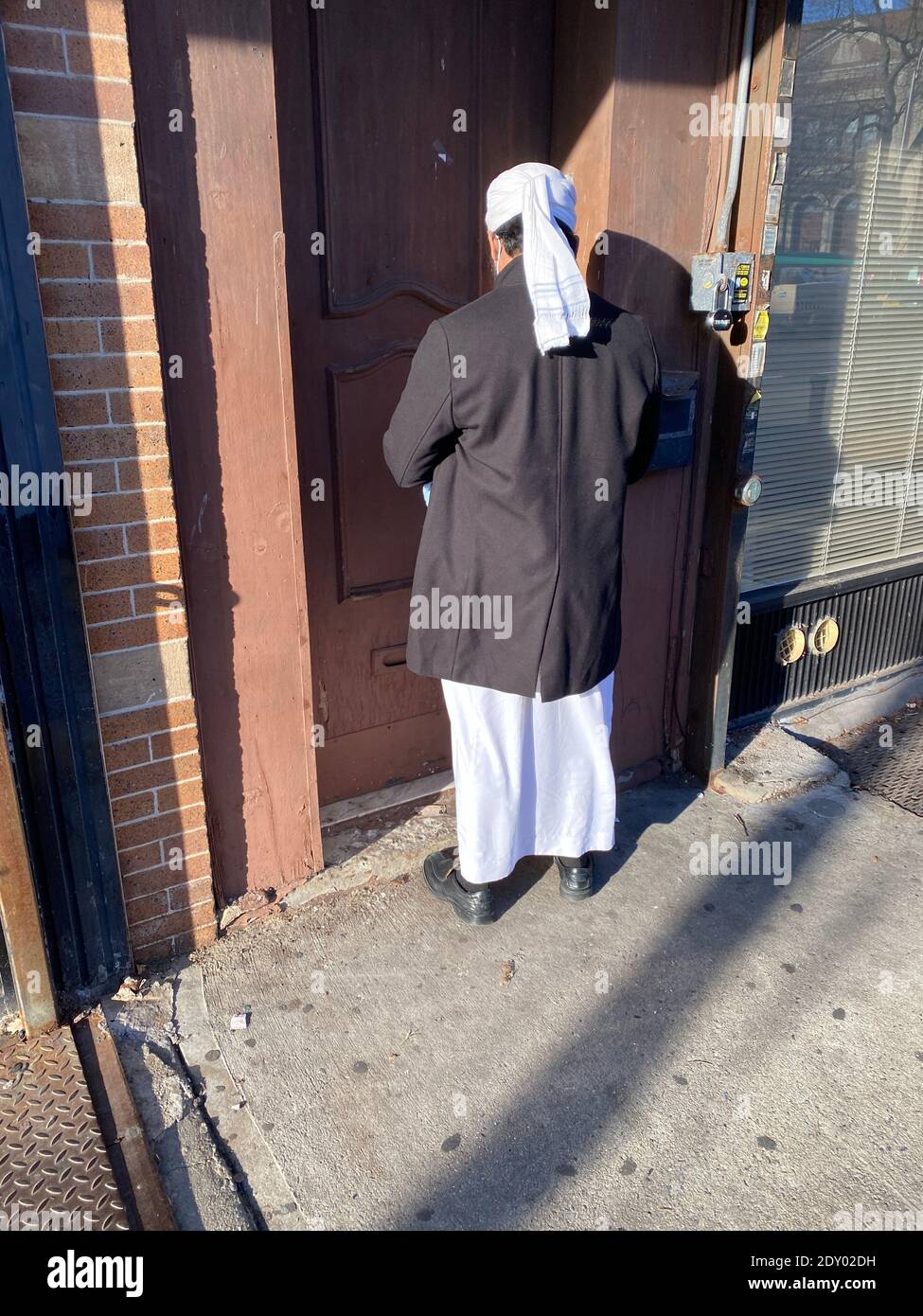 Muslim man in his prayer clothes returning home from the Mosque in the Kensington neighborhood of Brooklyn, New York. Stock Photo