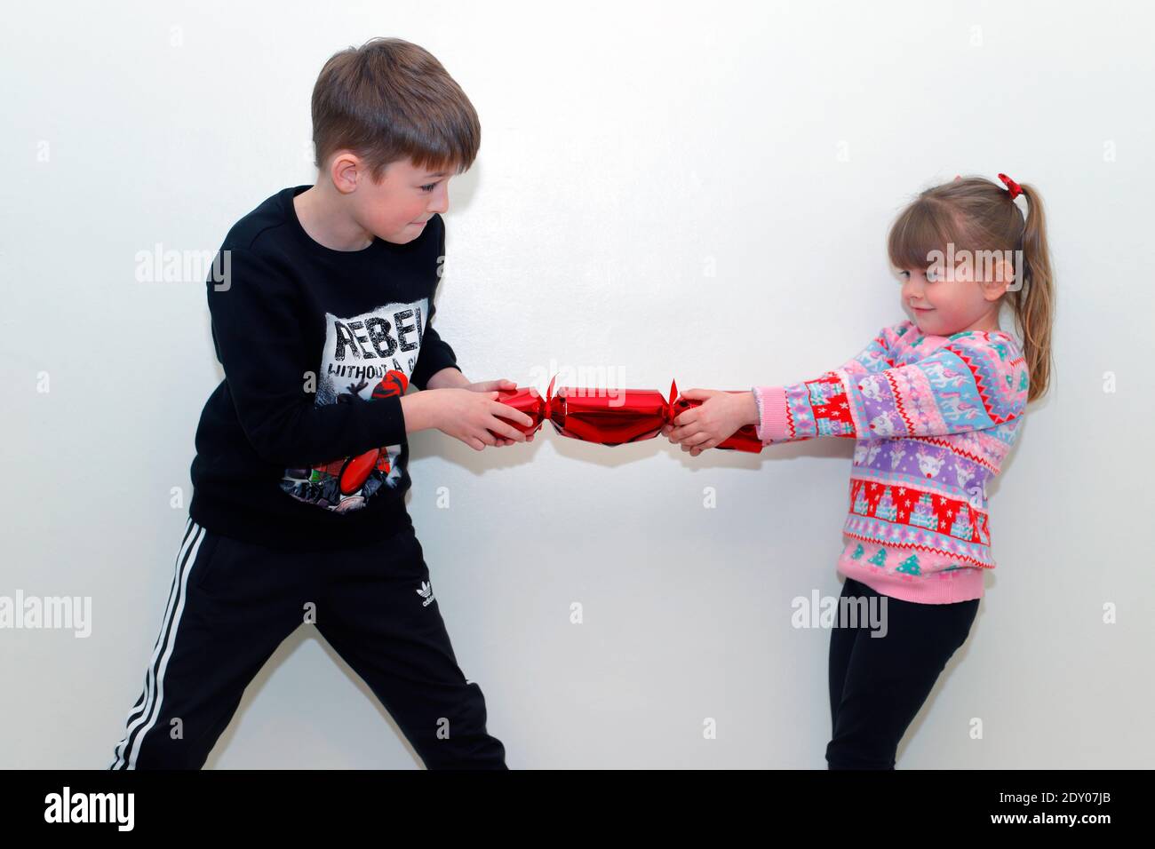 2 caucasian children pulling a Christmas cracker. Stock Photo