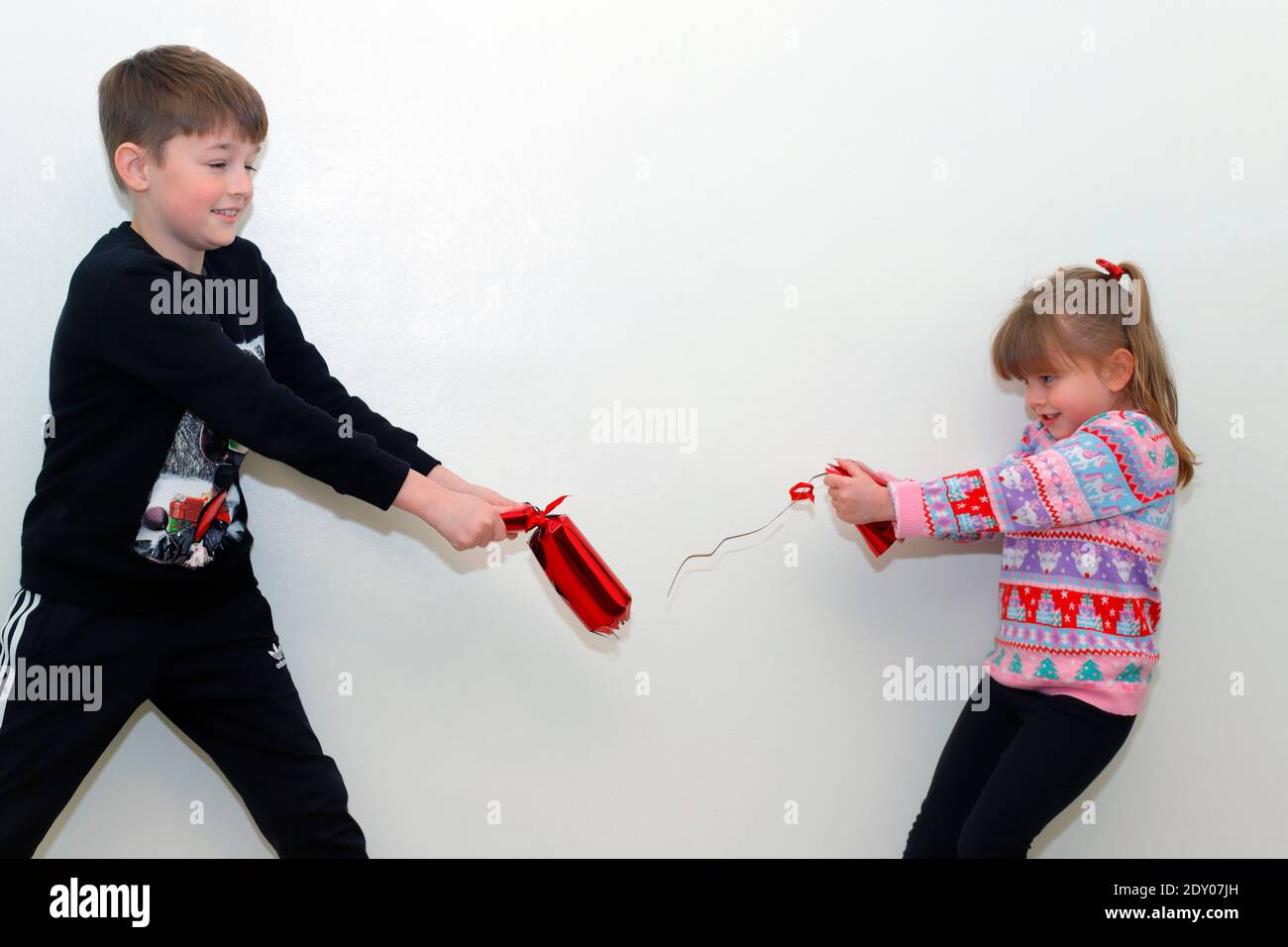 The moment a Christmas cracker breaks when a brother and sister Stock Photo
