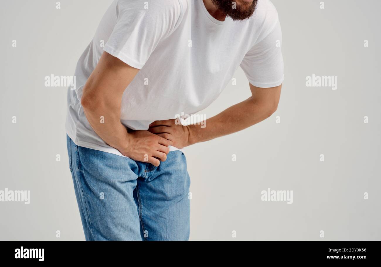 man experiencing pain below the belt in the groin and jeans tshirt