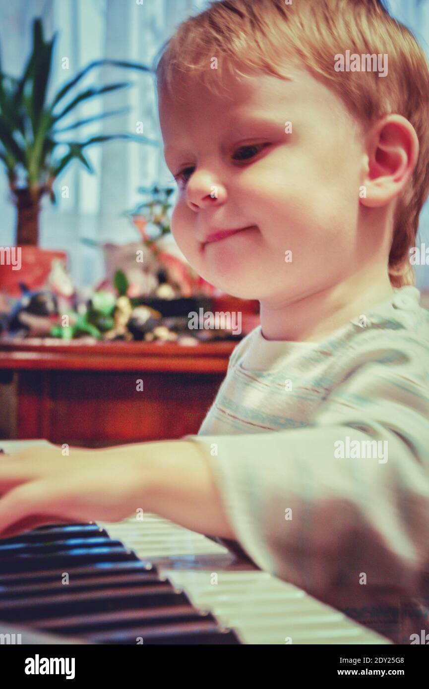 Cute Boy Playing Piano At Home Stock Photo
