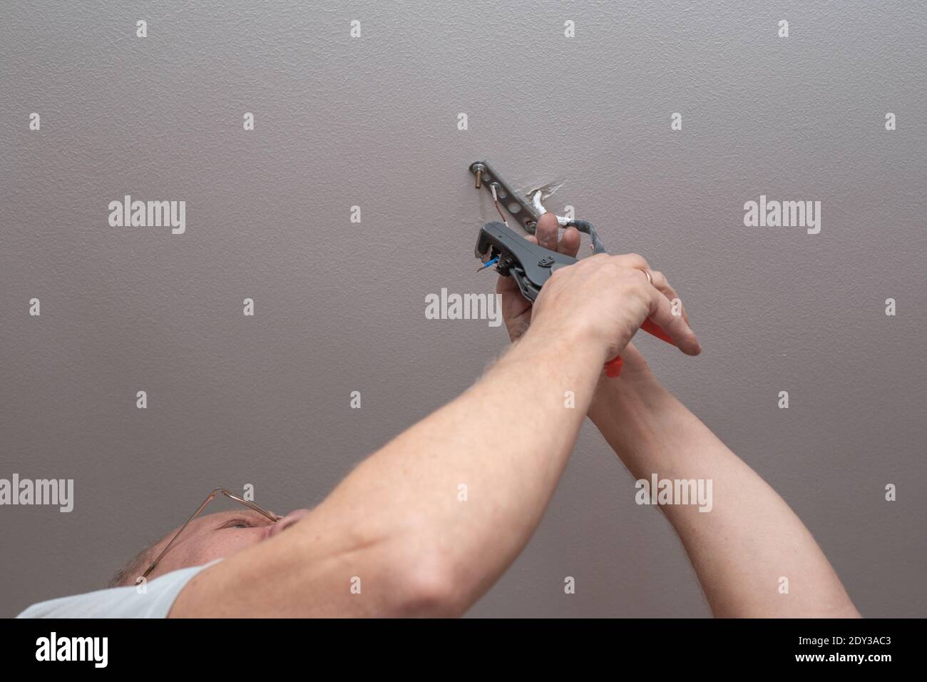 an adult man hangs a chandelier from the ceiling at home. Improvement and repair of premises. Stock Photo