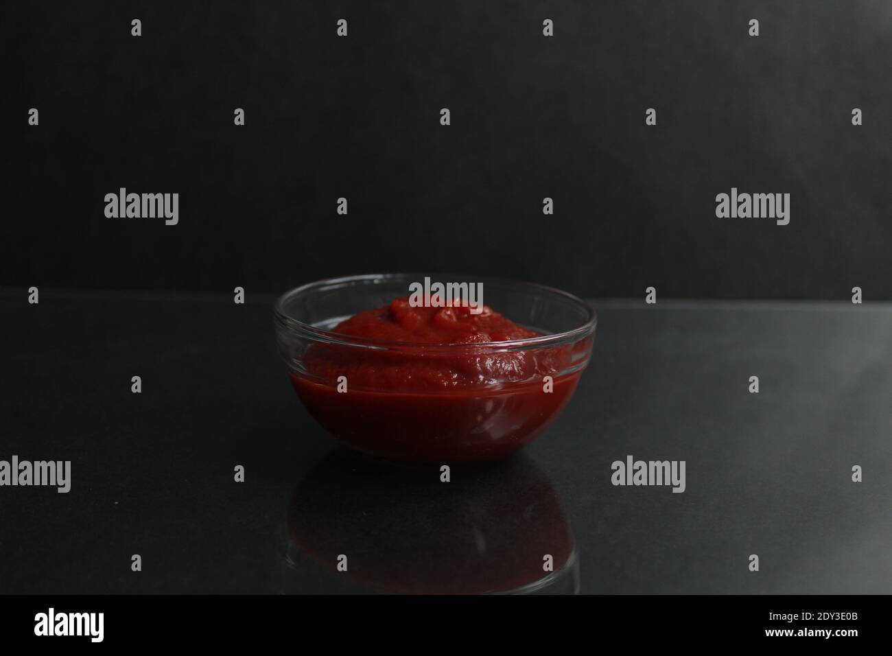 red tomato sauce paste in a glass sauce bowl on a black background copy space place for text. Stock Photo