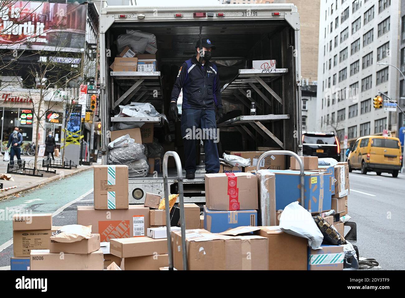 New York, USA. 24th Dec, 2020. Sprawled out on Second Avenue behind his truck, a FEDEX worker sorts out packages to be delivered on Christmas Eve, New York, NY, December 24, 2020. With a resurgence in COVID-19 infections, package shipping services such as FEDEX, UPS and the USPS are expecting to deliver a record number of packages for 2020. (Photo by Anthony Behar/Sipa USA) Credit: Sipa USA/Alamy Live News Stock Photo