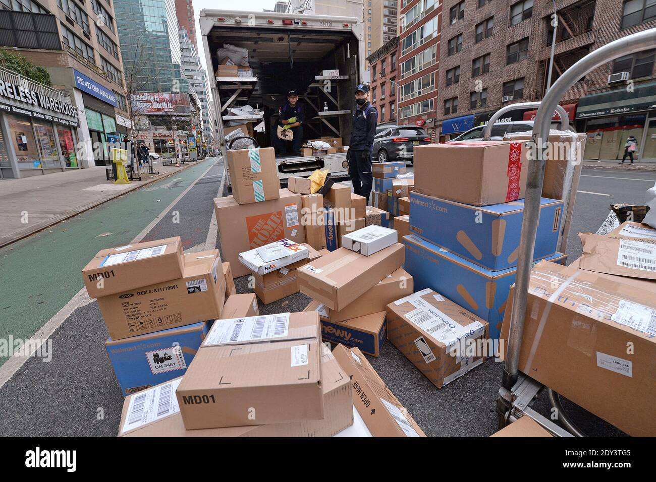 New York, USA. 24th Dec, 2020. Sprawled out on Second Avenue behind his truck, two FEDEX workers sort out packages waiting to be delivered on Christmas Eve, New York, NY, December 24, 2020. With a resurgence in COVID-19 infections, package shipping services such as FEDEX, UPS and the USPS are expecting to deliver a record number of packages for 2020. (Photo by Anthony Behar/Sipa USA) Credit: Sipa USA/Alamy Live News Stock Photo