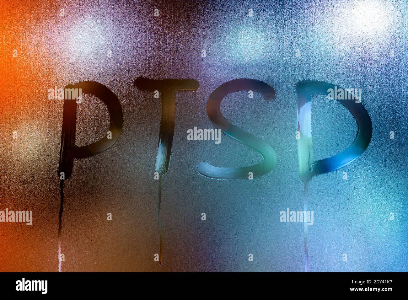 an abbreviation PTSD - post traumatic stress disorder - handwritten on wet glass of night window. Stock Photo