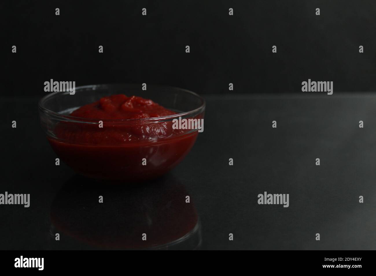 red tomato sauce paste in a glass sauce bowl on a black background copy space place for text. Stock Photo