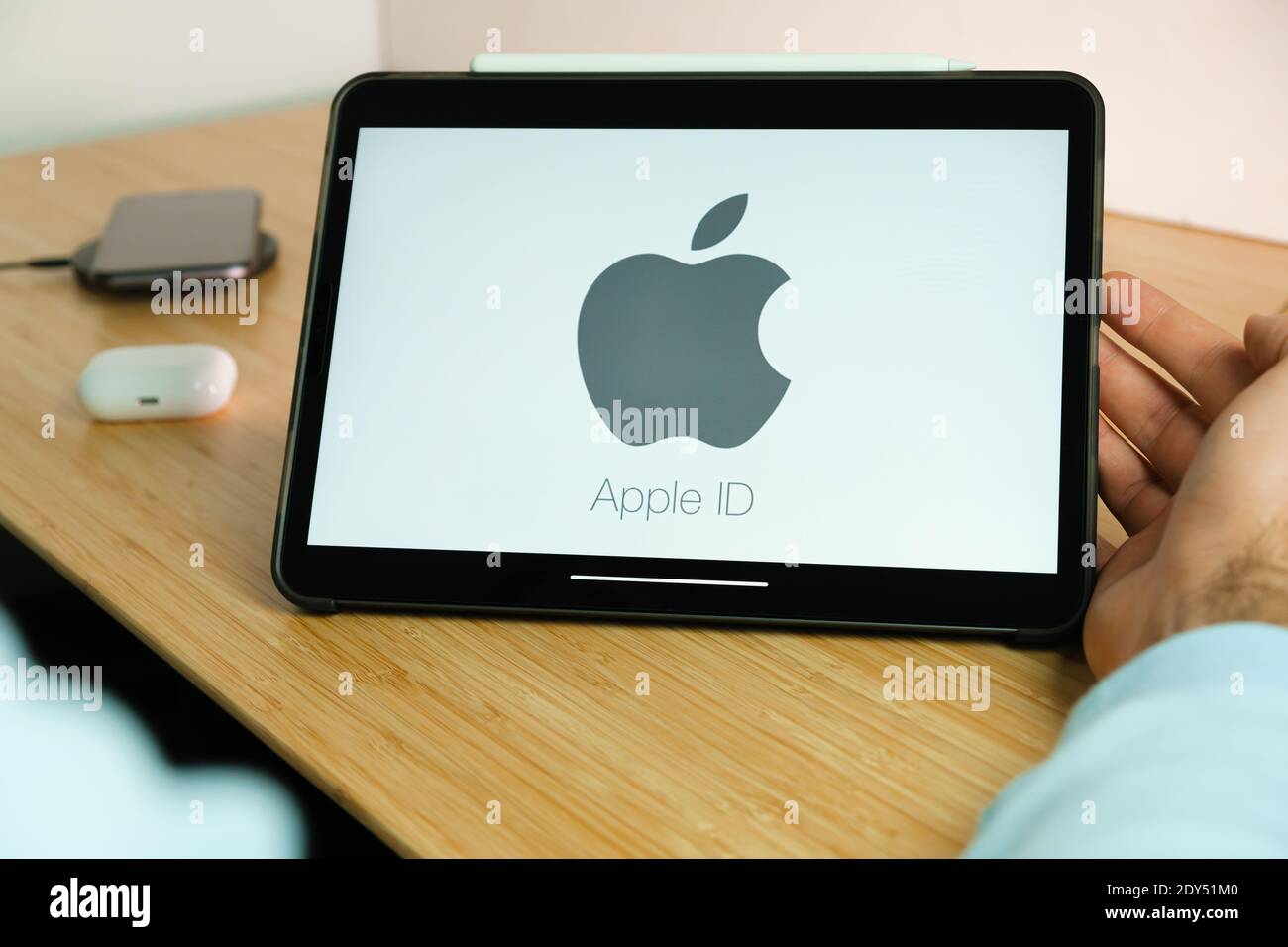 Apple ID logo on the screen of iPad tablet with smart phone iPhone charging  on the wireless charger and airpods in the case on the background Stock  Photo - Alamy