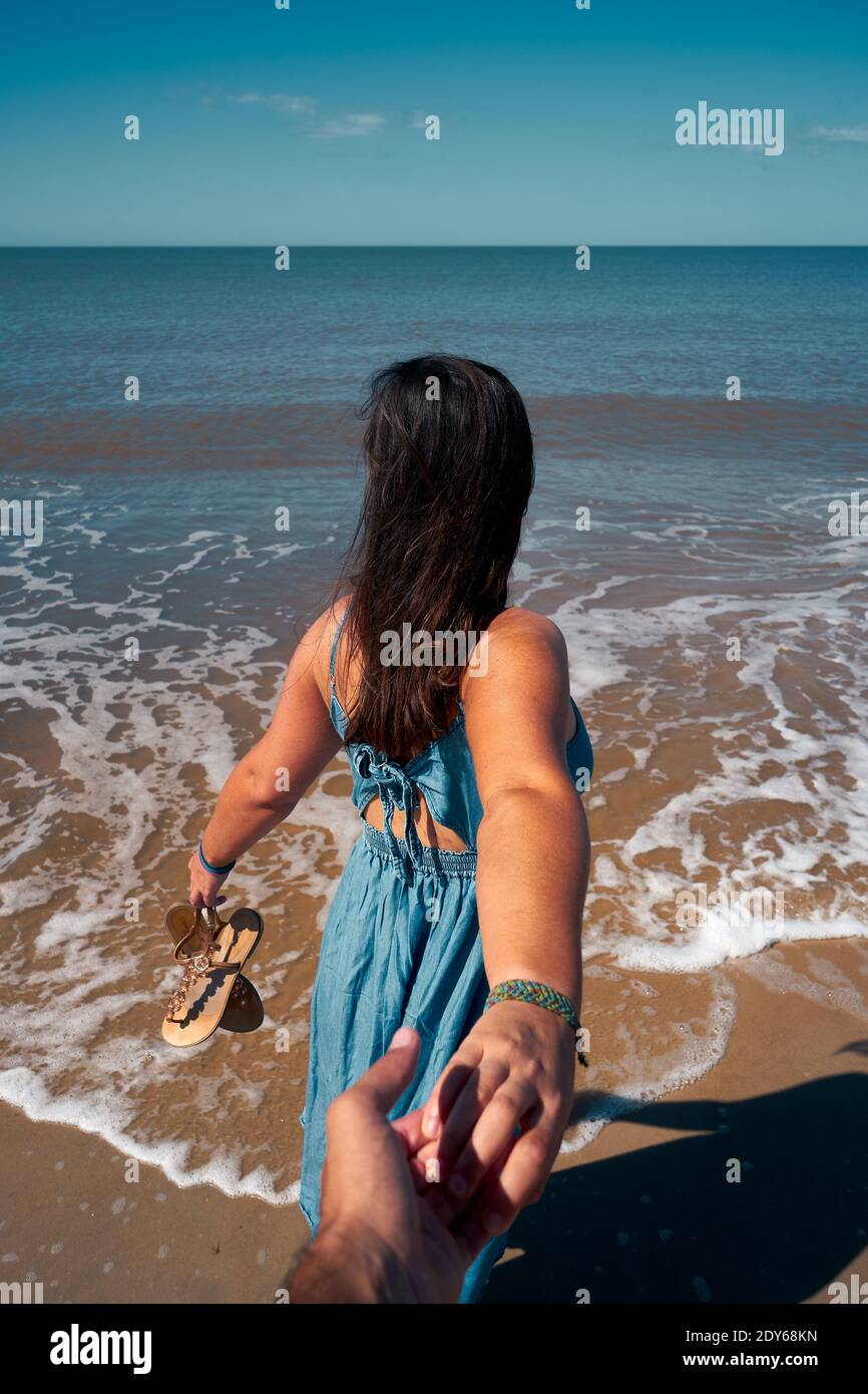 A romantic hand-holding shot of a couple on the beach, a backshot of a  female on the sea background Stock Photo - Alamy