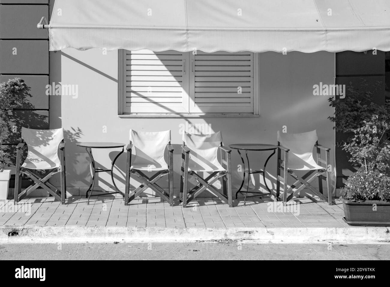 Front view of cafe exterior. Typical cafe. Empty chairs with table near coffee shop. Empty touristic place. Closed cafe. Black and white photos cafe. Stock Photo