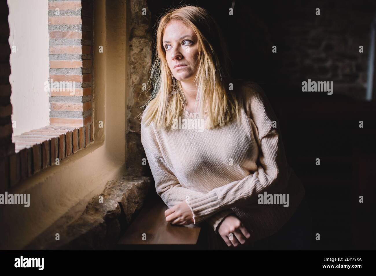 Young woman looking through a window Stock Photo