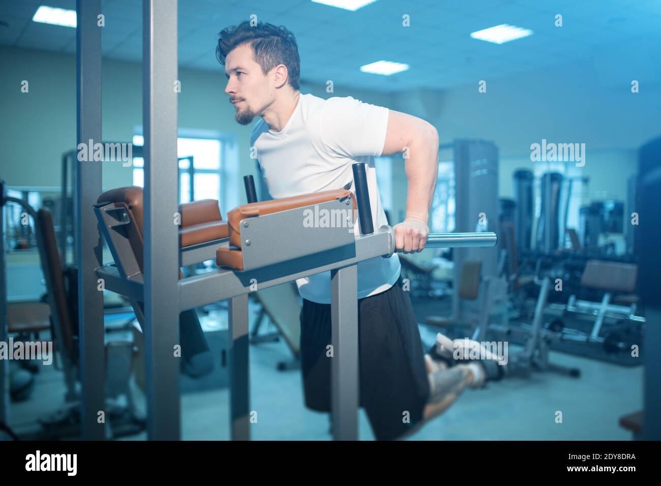young athletic male has personal workout and pull up on bar in gym ...