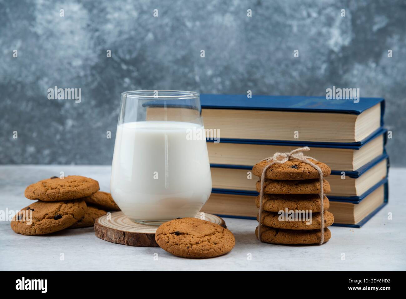 Glass of milk, sweet cookies and book on marble table Stock Photo