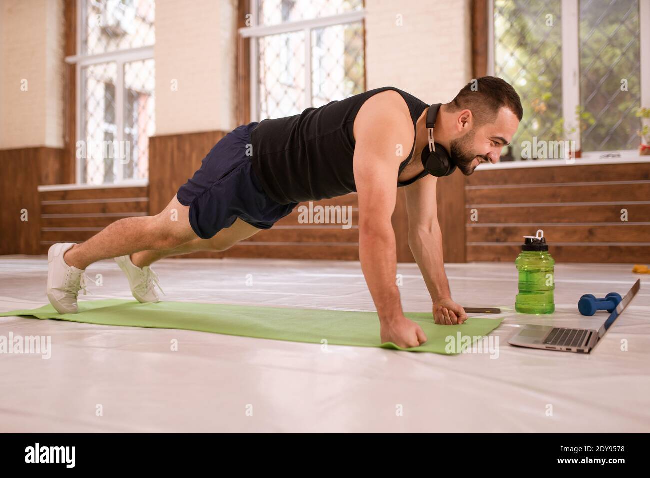 Fitness man in black sports wear doing up push ups exercise in empty gym or  home watching online sports videos. Muscular sportsman doing exercises  Stock Photo - Alamy