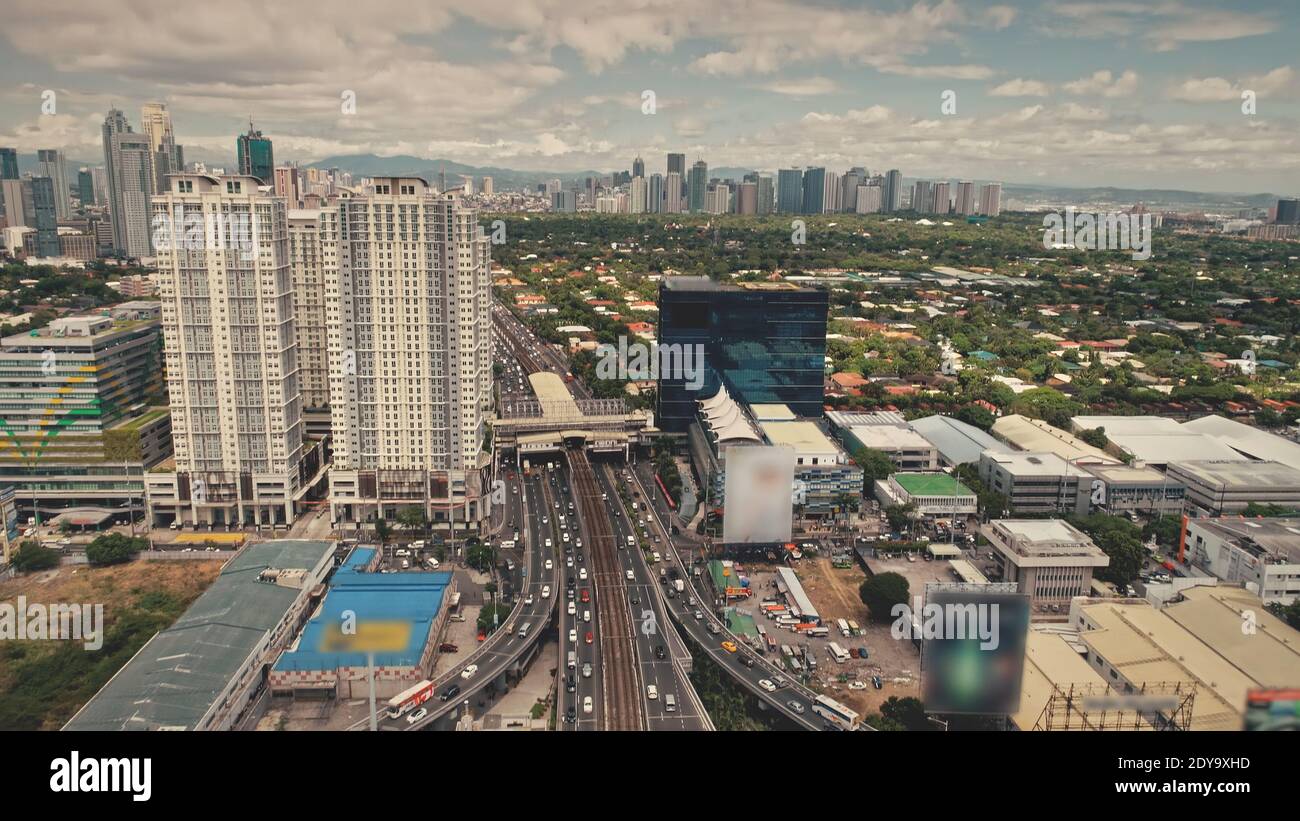 Modern skyscrapers aerial. Epic cityscape with streets along road. Block buildings and cottages at cloudy summer day. Downtown local transportation at Manila city, Philippine Stock Photo