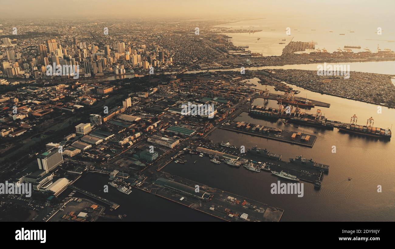 Sunset at metropolis port city at ocean bay aerial. Sun light at marina with ships, boats. Streets, roads at sunlight. Tropic cityscape of Manila capital town, Philippines. Epic nobody nature seascape Stock Photo
