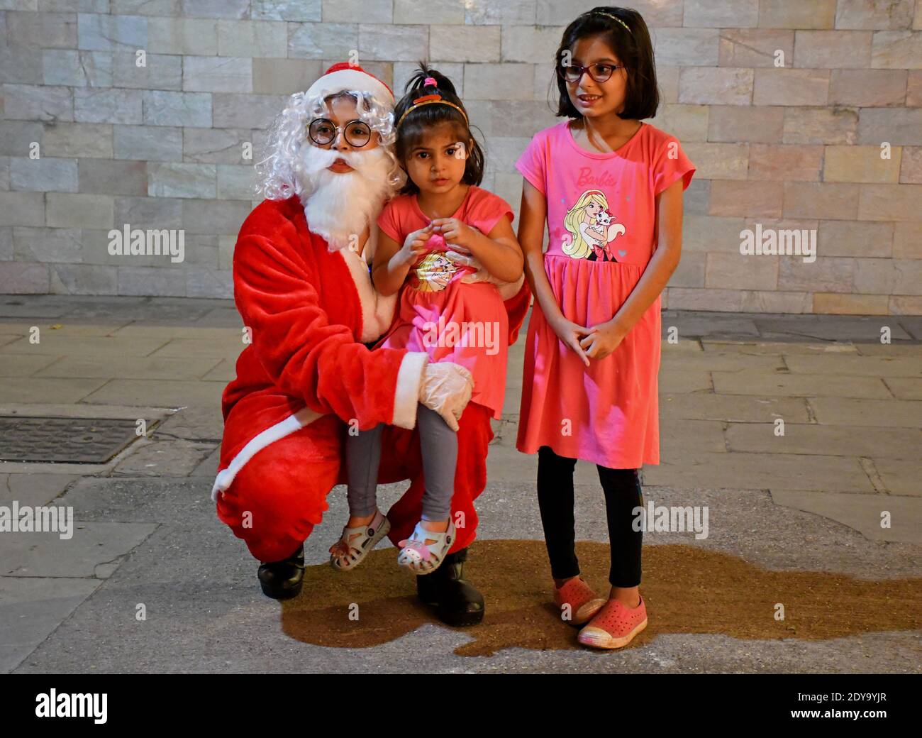 Mumbai, India. 24th Dec, 2020. A woman dressed as Santa Claus carries a young girl as they pose for a picture.Kavita Patil, a young woman dressed as Santa Claus spread happiness in this difficult time of coronavirus pandemic. She interacted with the children and posed for pictures. Credit: SOPA Images Limited/Alamy Live News Stock Photo