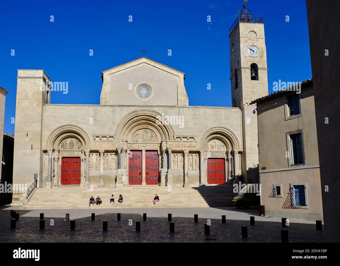 Outside of the  Abbatiale Saint-Gilles du Gard  in Saint-Gilles, with the city square where people assemble to meet on steps Stock Photo