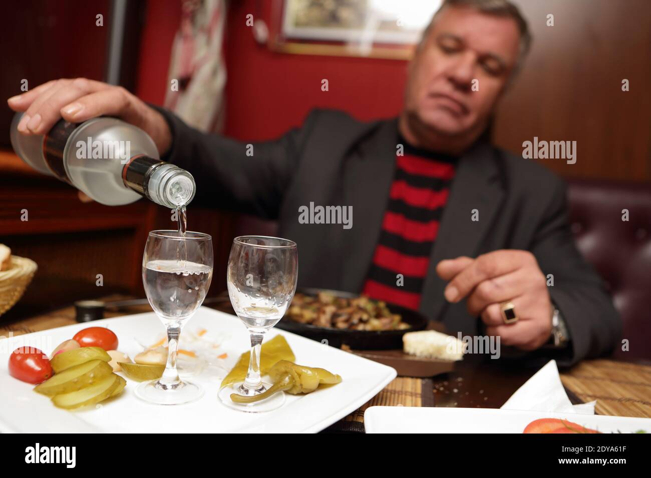 Senior man pouring vodka into glasses in pub Stock Photo Alamy