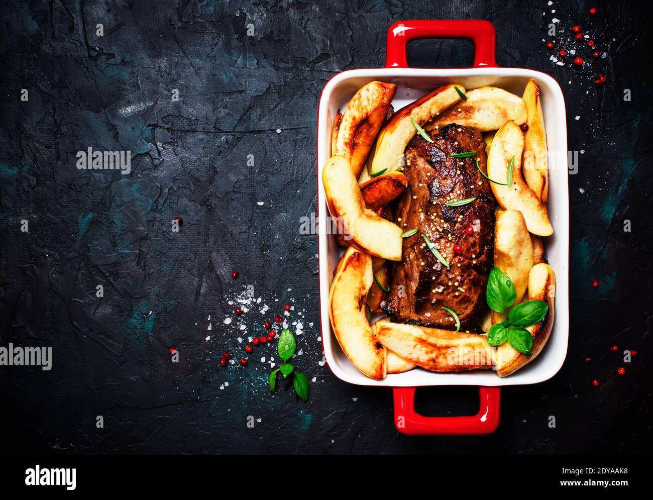 Pork tenderloin baked with quince on a baking sheet, gray background