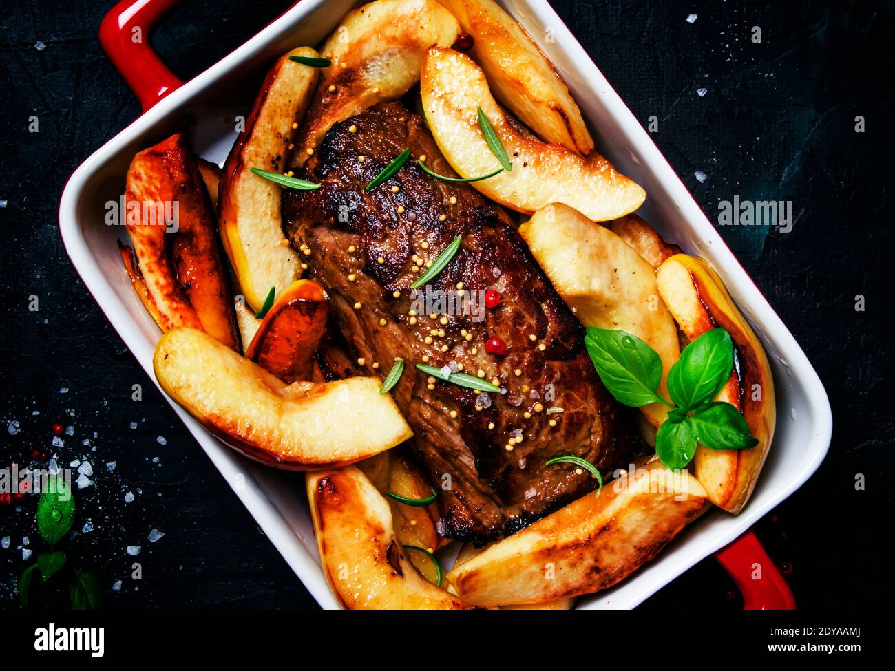 Pork tenderloin baked with quince on a baking sheet, gray background