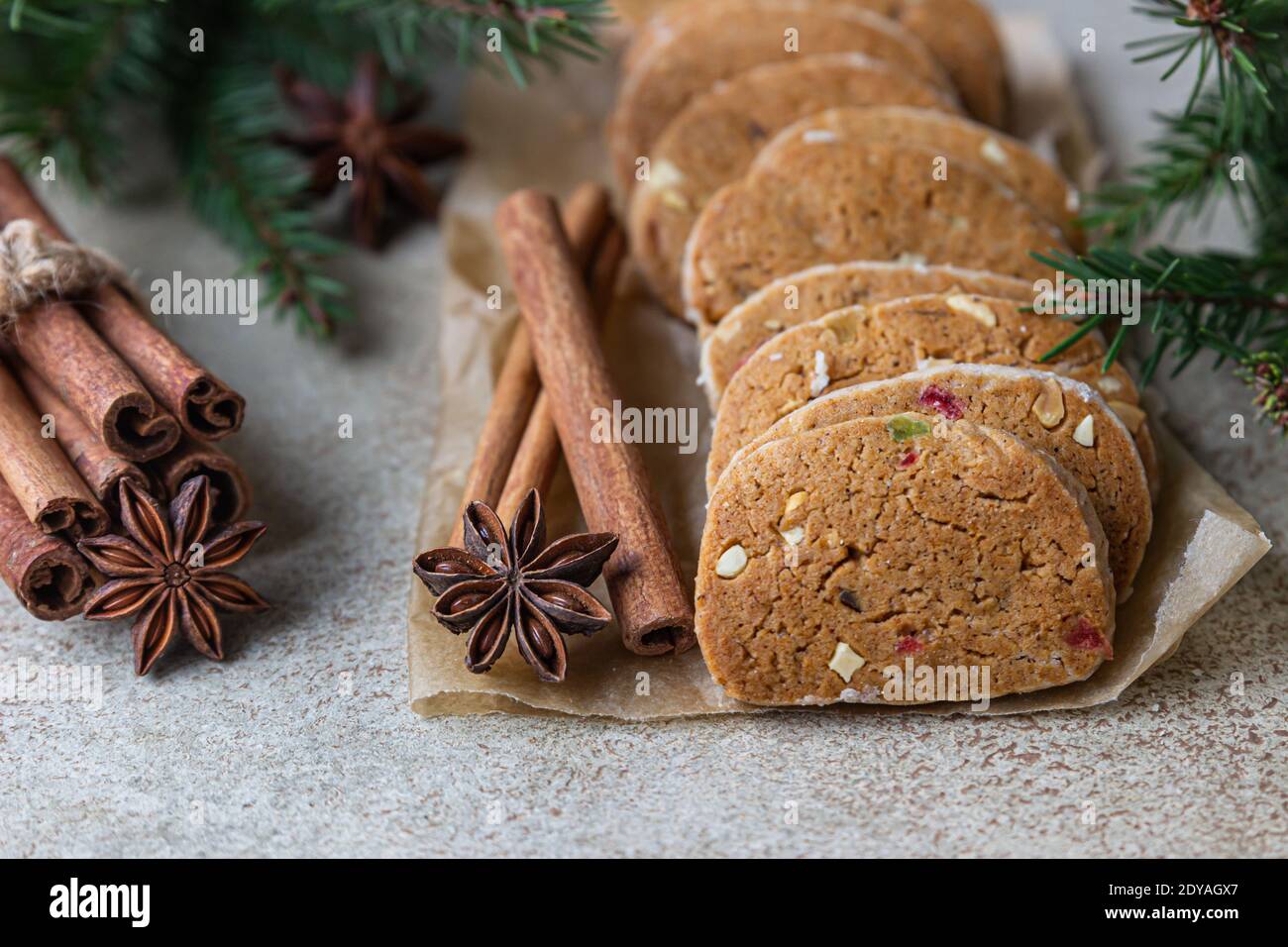 Danish spicy butter cookies with candied fruits, cinnamon sticks and anise, light background. Festive Christmas or New Year background with fir branch Stock Photo