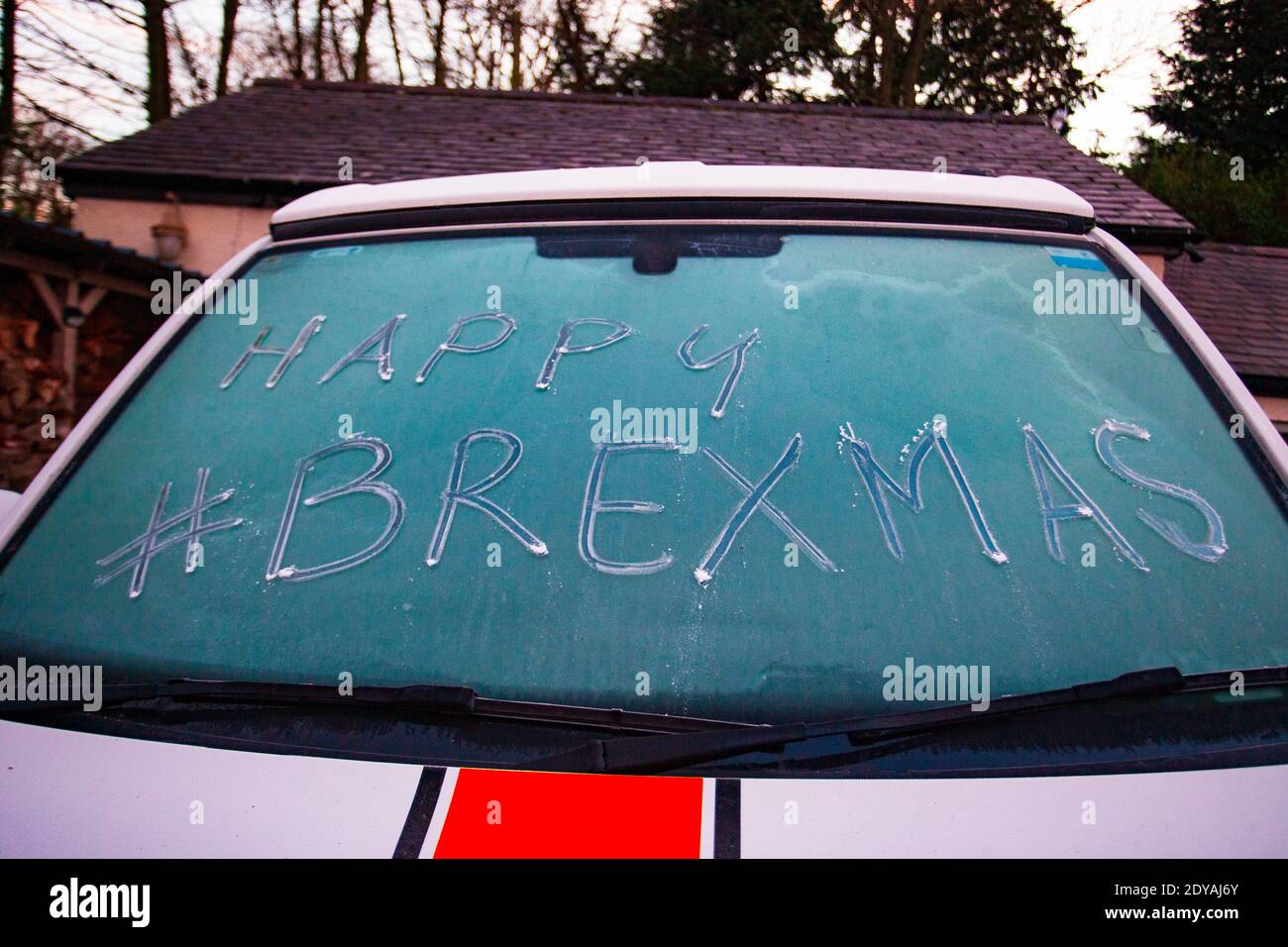 Halkyn, North Wales, UK 25th December 2020, A cold and frosty Christmas morning for many as an overnight frost has left many with either a sharp frost or even snow in the UK. Here in North Wales the temperature fell below zero to leave a morning frost allowing people to express their holiday notes in the windscreen ice as this driver did with Happy Brexmas © DGDImages/Alamy Live News Stock Photo