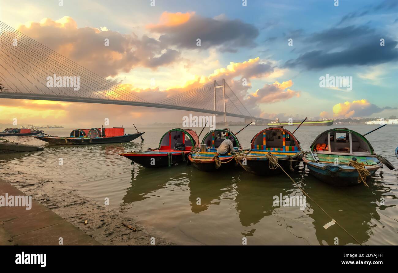 Wooden boats at Ganges riverbank with view of Vidyasagar setu cable stayed bridge at Kolkata India Stock Photo
