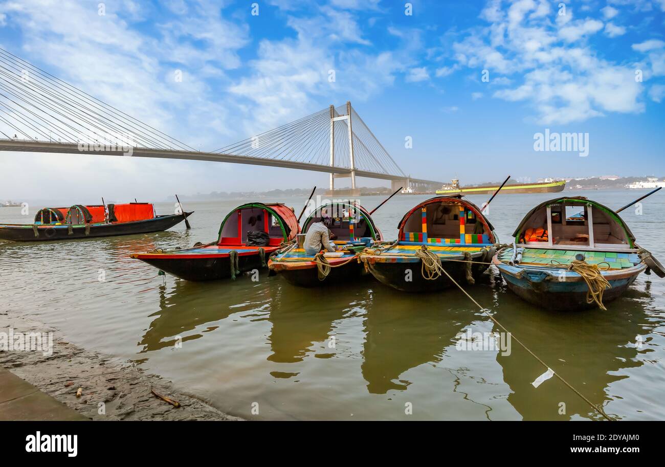 Wooden boats at Ganges riverbank with view of Vidyasagar setu cable stayed bridge at Kolkata India Stock Photo