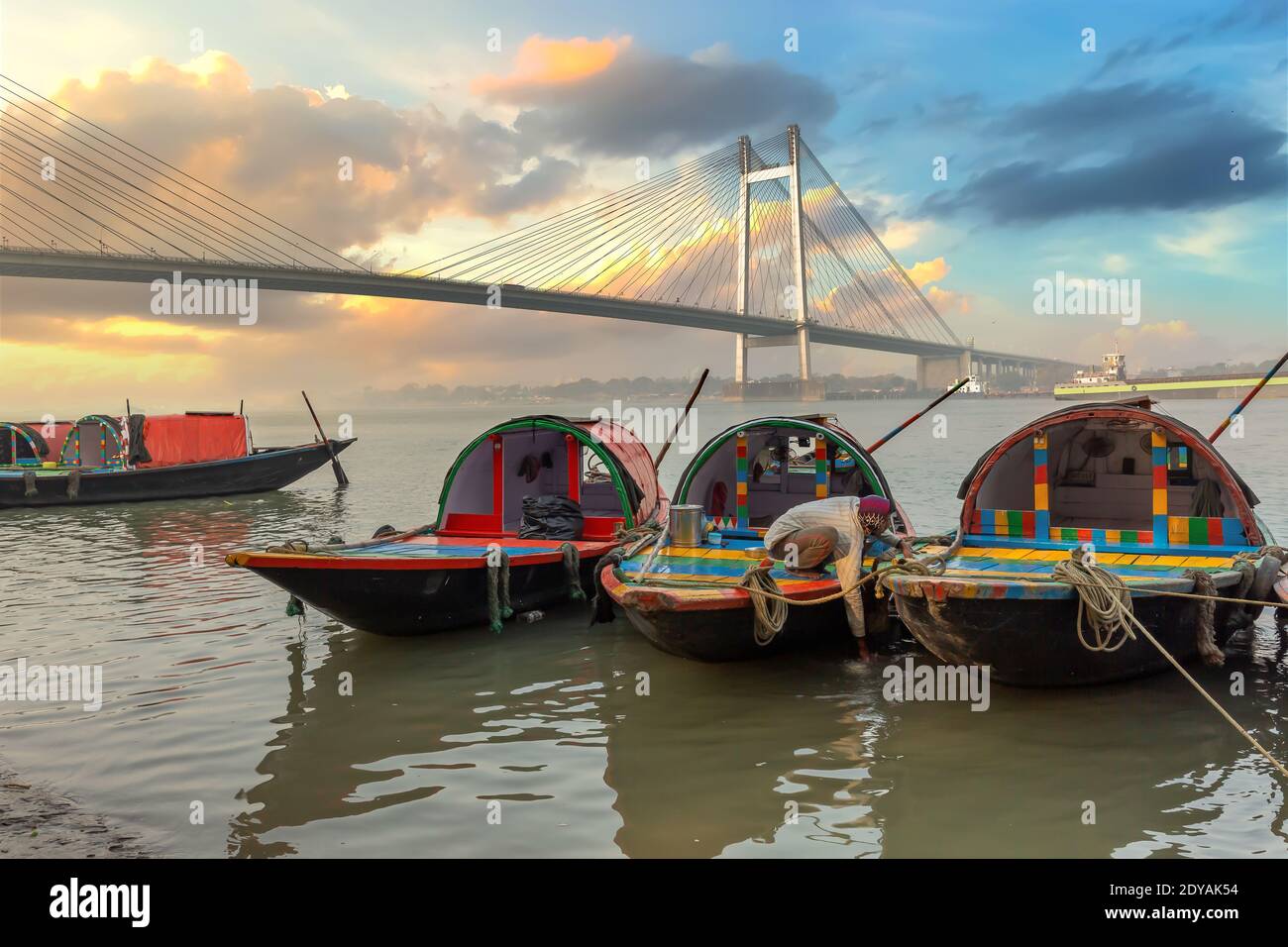 Wooden boats at Ganges riverbank with view of Vidyasagar setu cable stayed bridge at Kolkata India Stock Photo