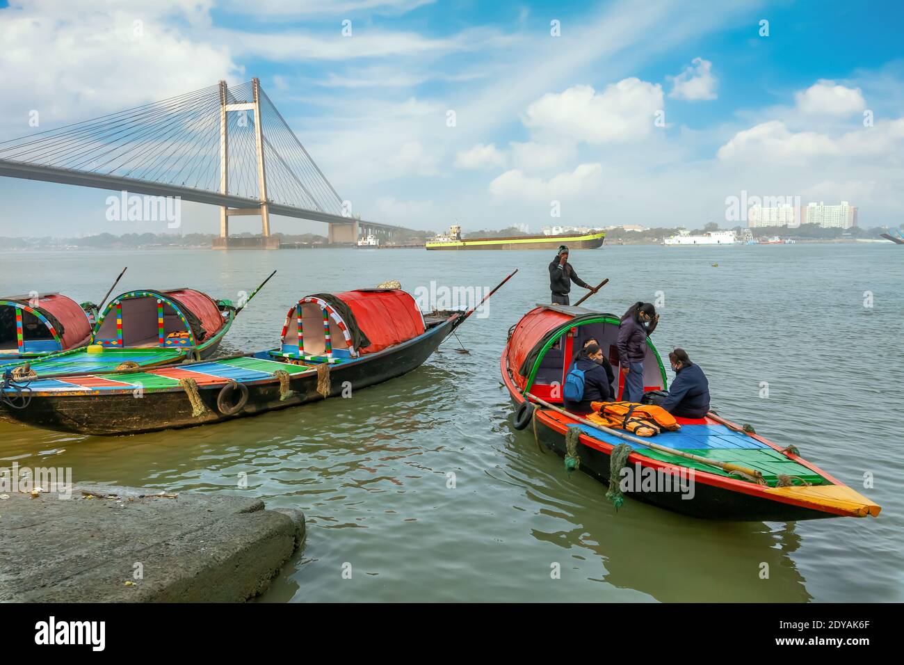 Wooden boats at Ganges riverbank with view of Vidyasagar setu cable stayed bridge at Kolkata India Stock Photo