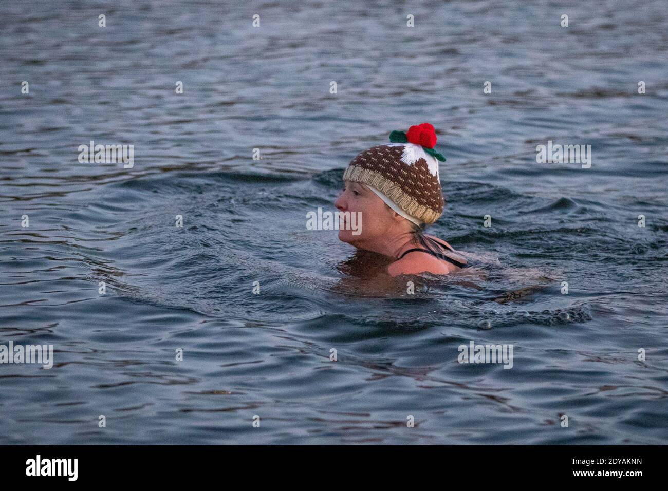 A swimmer in a Christmas pudding hat takes a Christmas Day dip at the