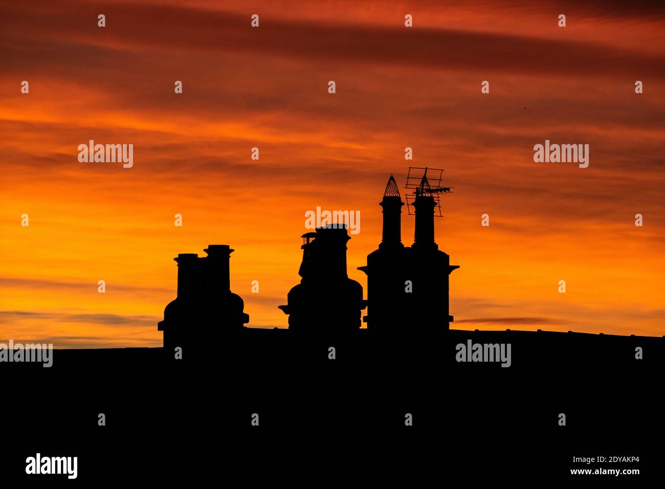 Silhouetted chimney pots against dramatic sunrise on Christmas day morning Stock Photo