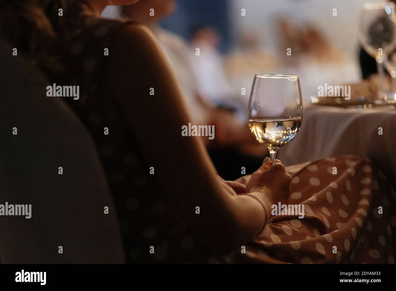 Faceless woman holding wine glass in her hand. Blurred background for your text Stock Photo