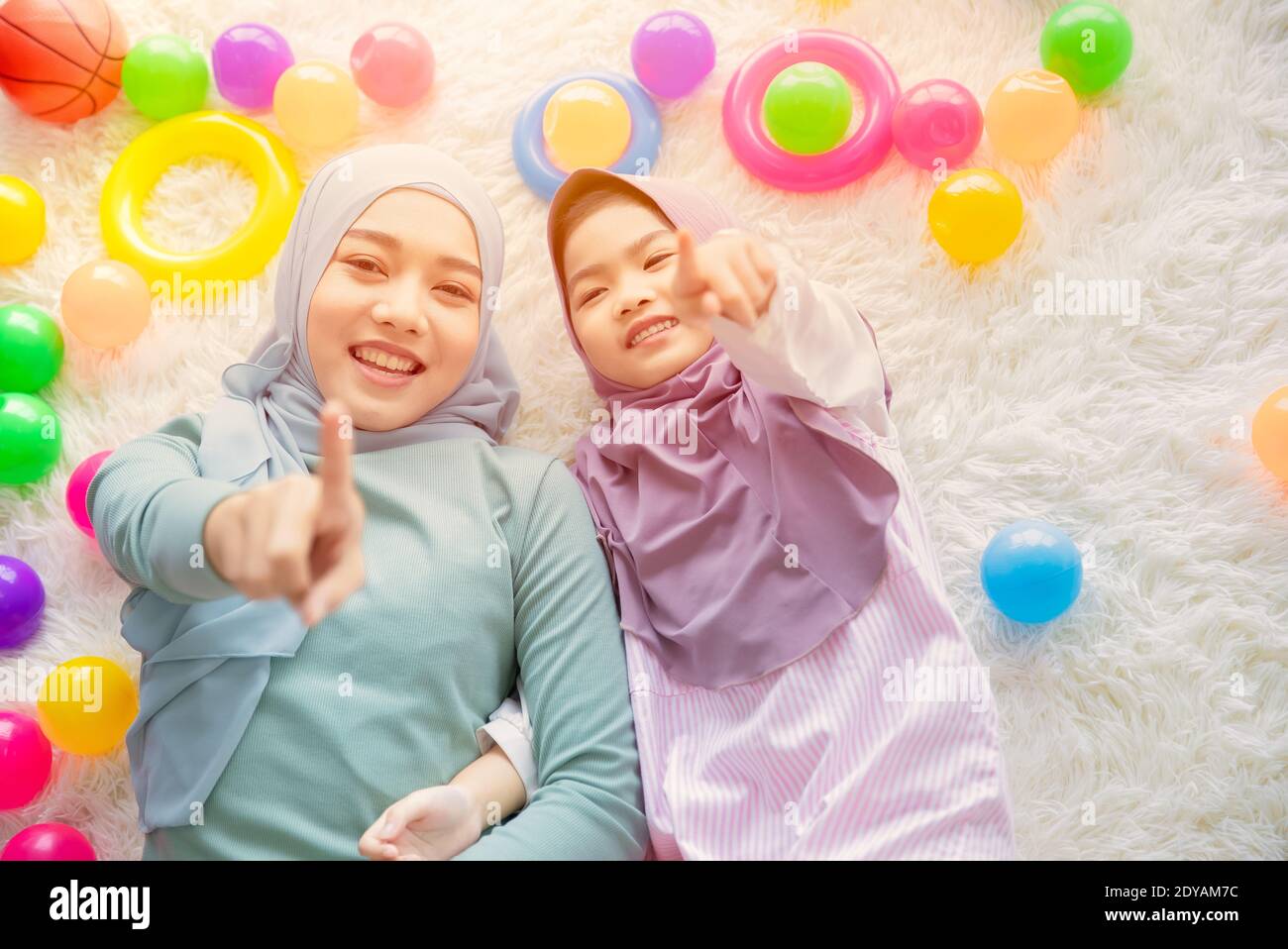 Cute Muslim Arab mother and her girl child happy playing together with colorful balls fun and lovely Stock Photo
