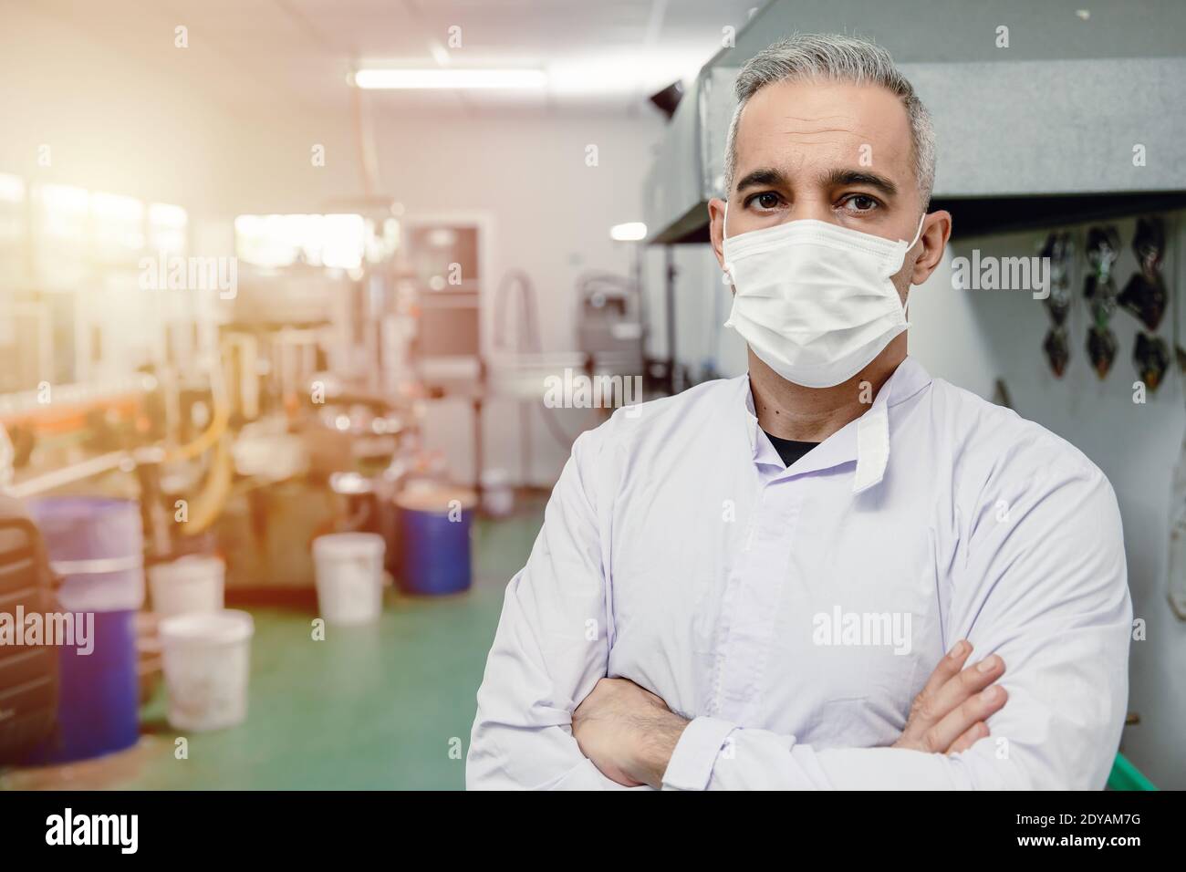 Confidence european high skilled worker middle age 40-50 standing portrait in factory with face mask. Stock Photo