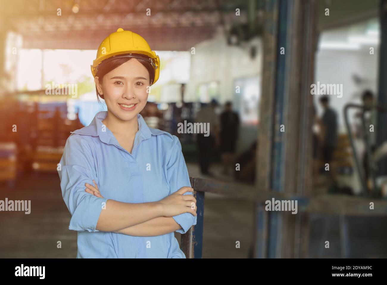 Young Asian smart woman working as foreman head engineer manager at logistic warehouse portrait smiling arms crossed. Stock Photo