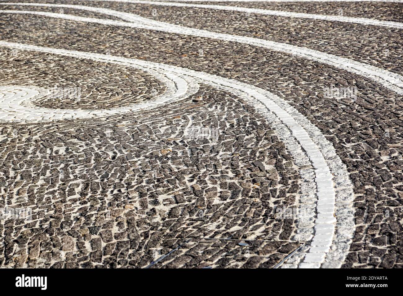 Background image of old cobblestone road backlit with low sunlight. Stone texture close up. Small pebbles on the road. Stone path Stock Photo