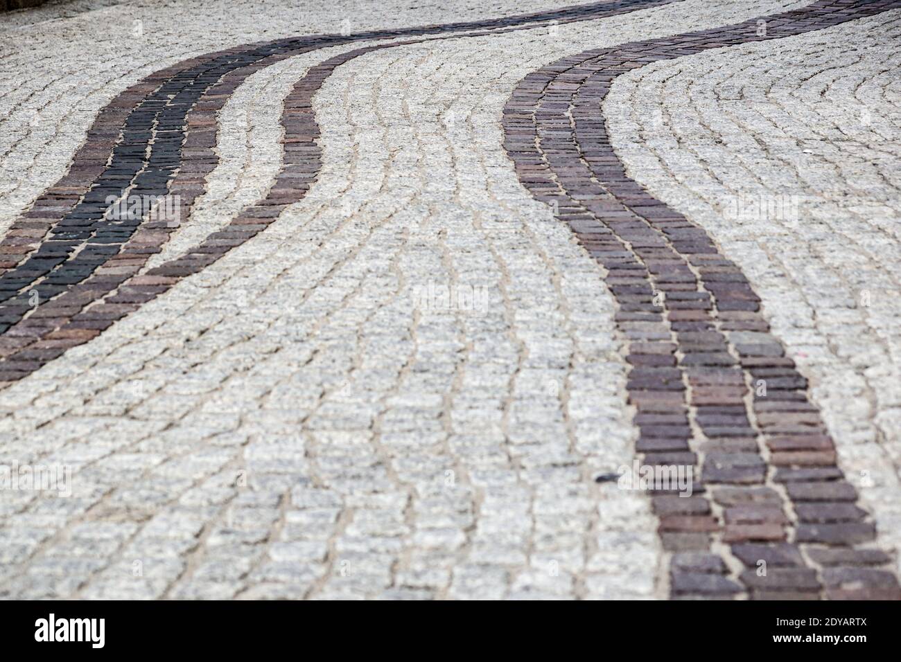 Background image of old cobblestone road backlit with low sunlight. Stone texture close up. Small pebbles on the road. Stone path Stock Photo