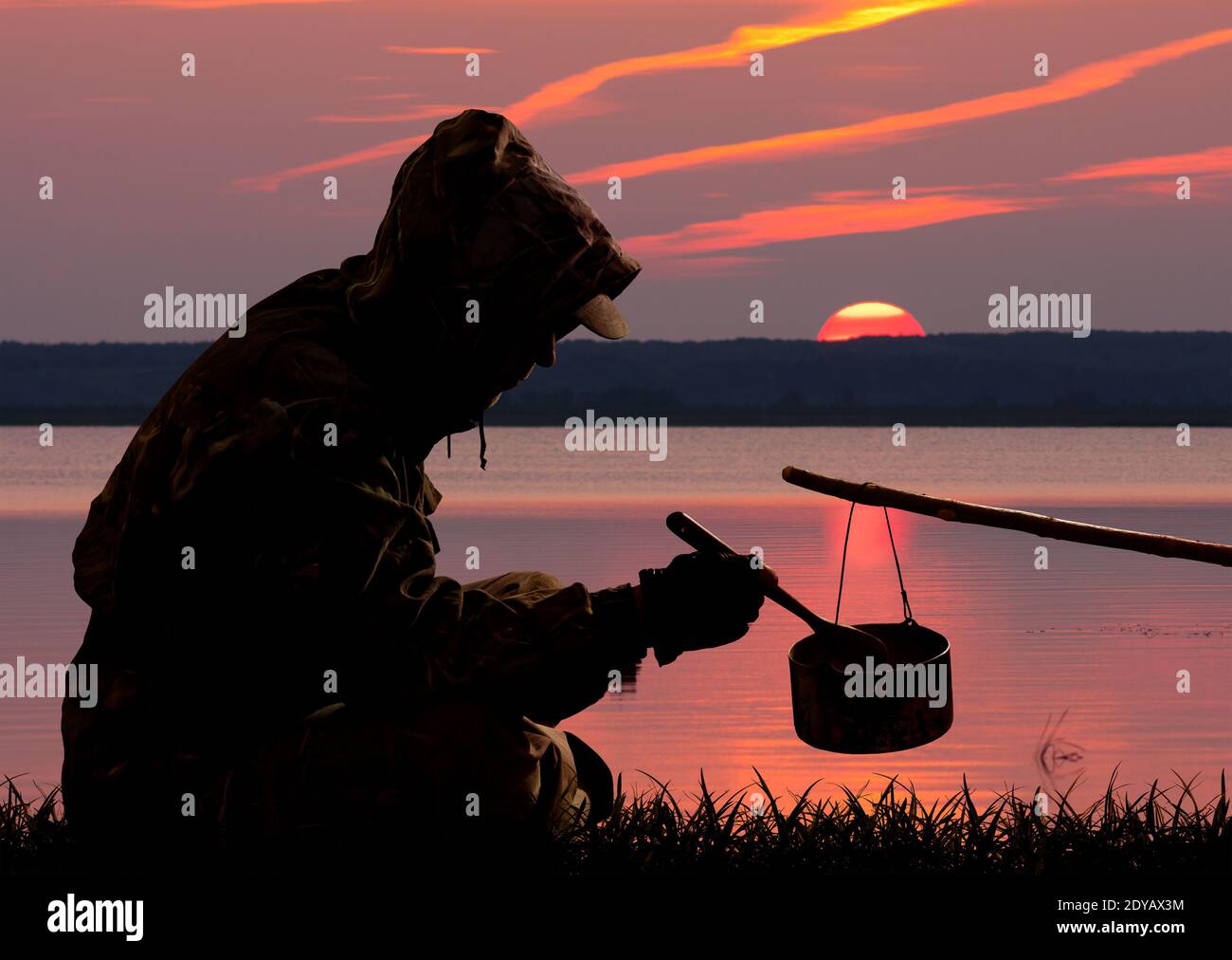 the silhouette of a hunter who dines against the sunset on the lake Stock Photo