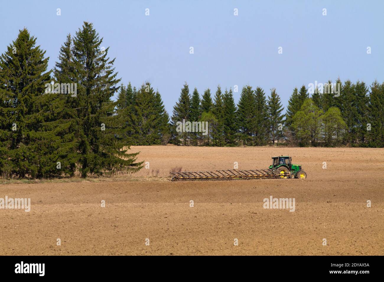 tractor with harrow working on the ploughed field in the spring Stock Photo