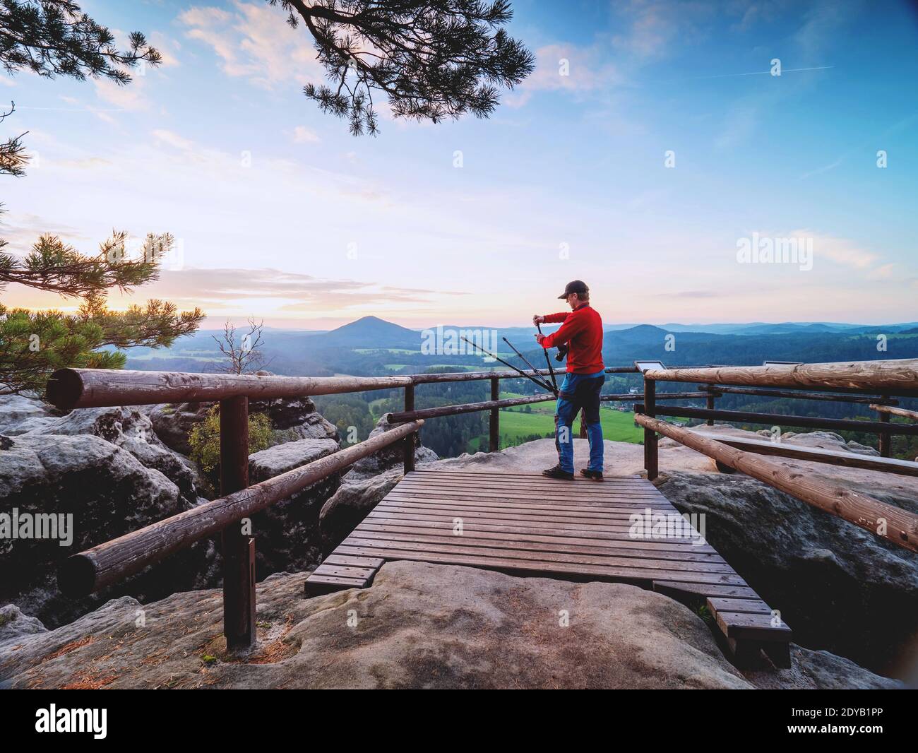 Hiker Setting Tripod Legs Upside Down With Camera In Ball Head. Hurry