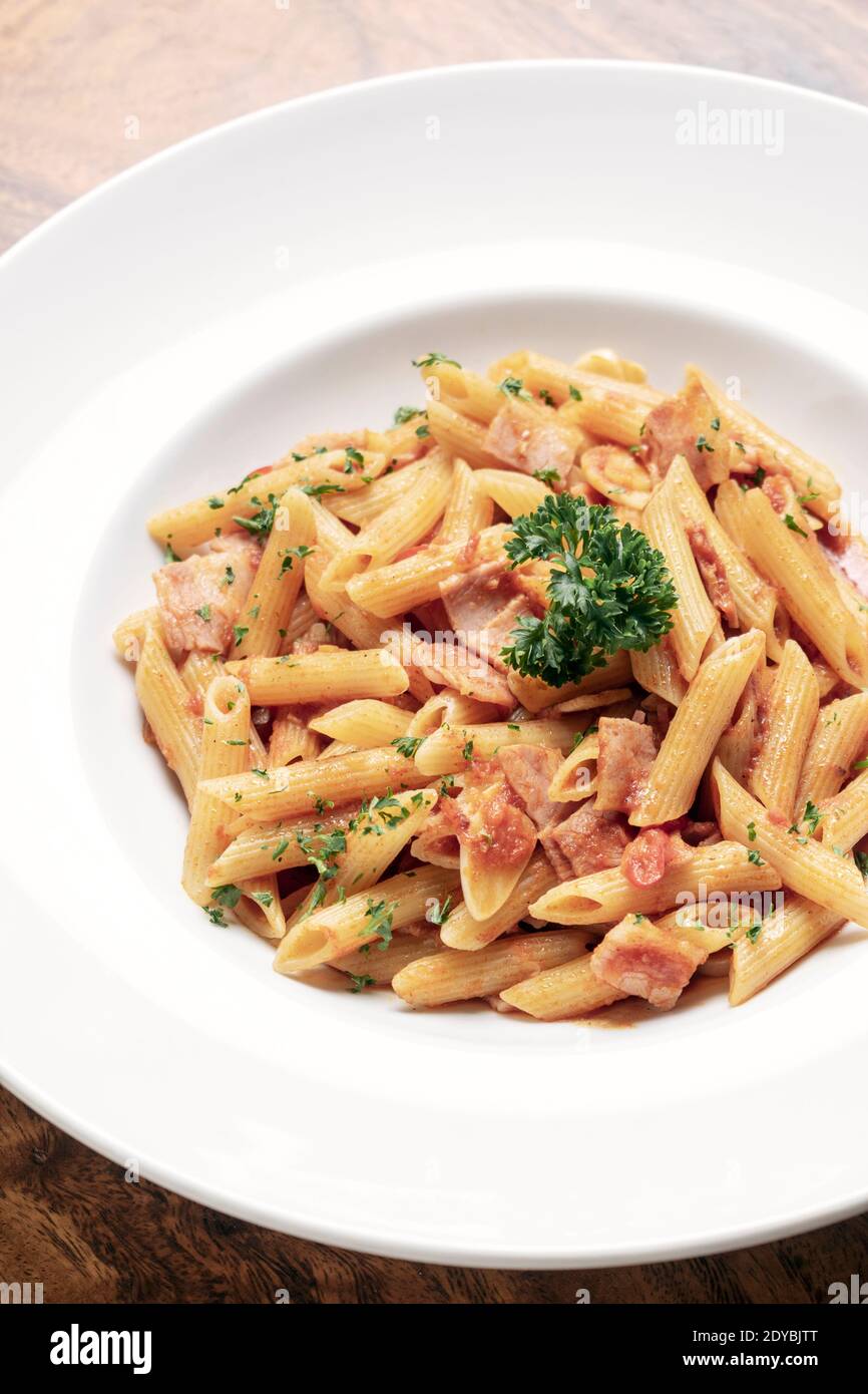 penne amatriciana tomato and ham sauce pasta on wood table background Stock Photo